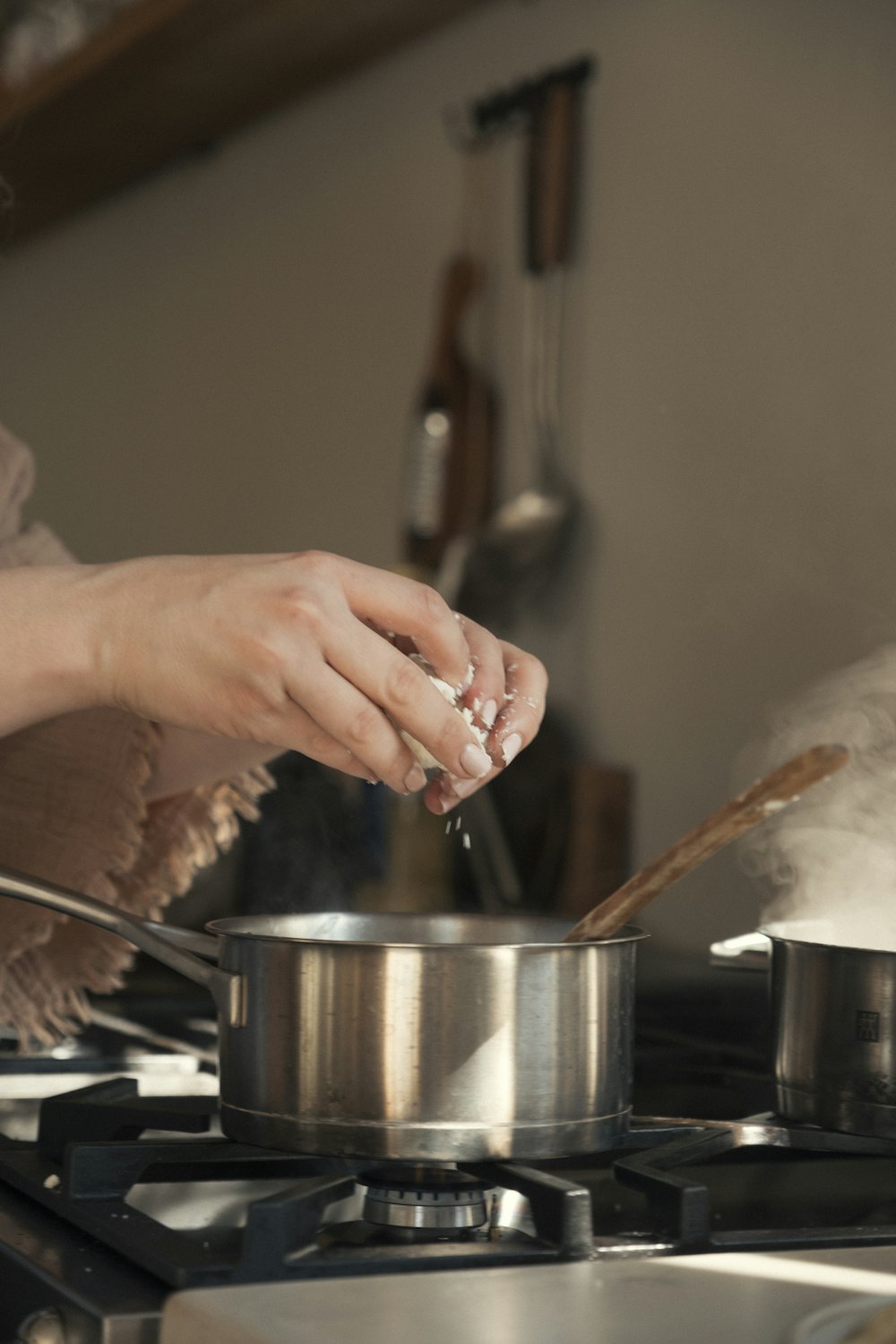 A cook tipping chopped ingredients from a board into a pot on the stove
